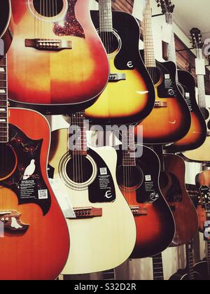 Chitarre acustiche appese per la vendita a parete in negozio di musica Foto Stock