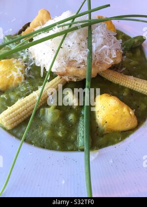 Più vicino di un entrée gourmet di risotti di asparagi verdi sormontati con mais del bambino, fiori di zucca, erba cipollina e zucca patty della padella, Stati Uniti Foto Stock