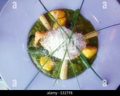 Piatto primo piano di risotti di asparagi verdi serviti con mais, fiori di zucca e zucca patty pan, Stati Uniti Foto Stock