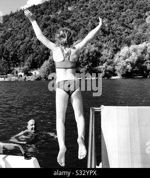 Ragazza con le braccia distese saltando da un pedalo nel Lago di Scanno, Italia Foto Stock