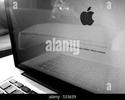 Aggiornare la schermata sul computer portatile Apple MacBook con la barra di avanzamento che mostra 1 minuto per andare e il logo Apple in bianco e nero Foto Stock