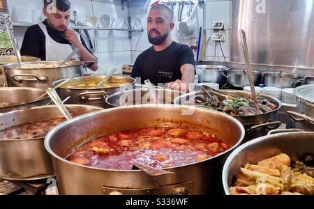 Un cuoco tende a pentole di cibo nella cucina del ristorante Azura nel mercato Mahane Yehuda di Gerusalemme. Foto Stock