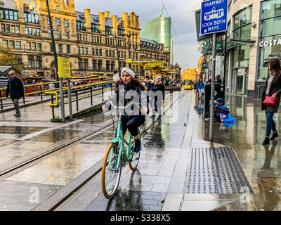 Andare in bicicletta dopo la fermata del tram Exchange Square a Manchester Foto Stock