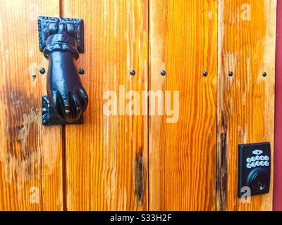 Un batticalcchiere pesante di secolo con una serratura moderna di combinazione su una porta di legno Foto Stock