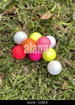 Varietà di palline da golf colorate su sfondo verde erba Foto Stock