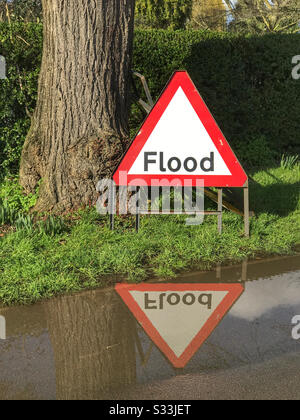 Segnale di allarme alluvione riflesso nell'acqua alluvionale proveniente dal fiume Severn lungo New Road, accanto al campo da cricket di Worcester, Regno Unito. Foto Stock