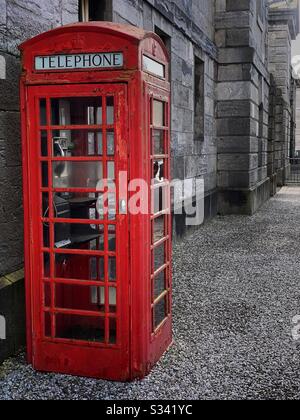 Scatola telefonica rossa britannica contro pareti in pietra Foto Stock