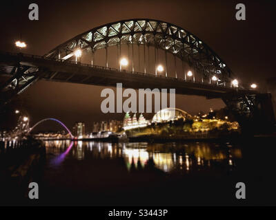 Una vista notturna del Tyne Bridge, del Sage Gateshead e del Millennium Bridge che si riflette nel fiume Tyne a Newcastle upon Tyne, Inghilterra del Nord Est Foto Stock