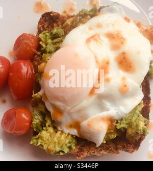 Uova in camicia e avocado su pane tostato con pomodori ciliegini Foto Stock