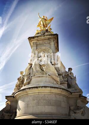 Una vista ad angolo basso del Victoria Memorial con la statua della Regina Vittoria sotto un cielo blu con i contrasti dell'aeroplano Foto Stock