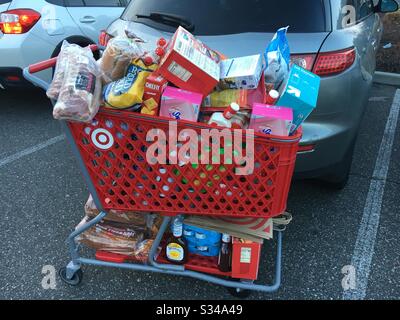 Un carrello rosso Target pieno di generi alimentari in un giorno in cui i clienti panico e articoli da barba. Foto Stock