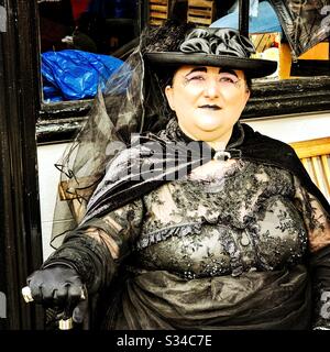 Persona in un costume creativo durante un evento cosplay. Weekend di Whitby Goth. Grande donna in nero Halloween gothic witch vestito Foto Stock