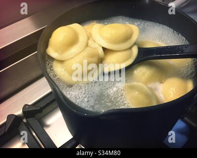 Ravioli freschi bollendo su un bruciatore residenziale di cima di stufa Foto Stock