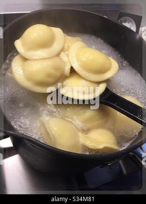 Ravioli freschi bollendo su un bruciatore residenziale di cima di stufa Foto Stock