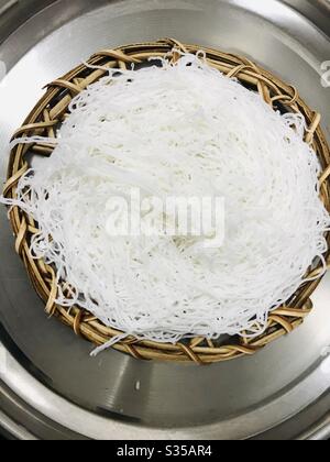 Trecce di riso o idiyappam aka Noolappam, pasta fatta in casa di farina di riso semi al vapore in Eco-friendly mano fatta mano foglia di palma piatto di ricetta Sud indiano-idiyappam con colore naturale, colazione indiana Foto Stock