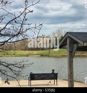 DUBUQUE, IOWA, 22 aprile 2020 --Foto di paesaggio dei pescatori soliti seduti sul banco del parco vicino stagno nel parco il giorno della Terra. Foto Stock