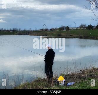 DUBUQUE, IOWA, 22 aprile 2020 --Foto di paesaggio di pescatori soliti che pescano dalla riva di uno stagno nel parco il giorno della Terra. Foto Stock