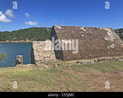 Powder Magazine a Fort Berkeley ad Antigua e Barbuda, Caraibi, Antille minori, Indie Occidentali con il Porto Inglese sullo sfondo e lo spazio delle copie del cielo blu. Foto Stock