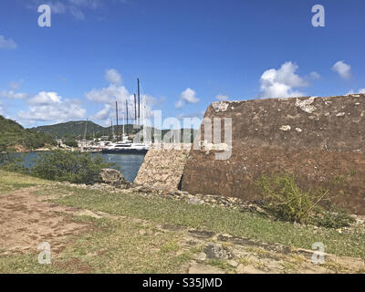 Powder Magazine a Fort Berkeley ad Antigua e Barbuda, Caraibi, Antille minori, Indie Occidentali con il Porto Inglese sullo sfondo e lo spazio delle copie del cielo blu. Foto Stock