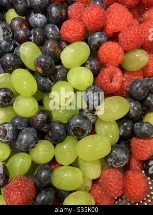 Macedonia di frutta fresca: Uve verdi, lamponi e mirtilli in un colino d'argento. Foto Stock