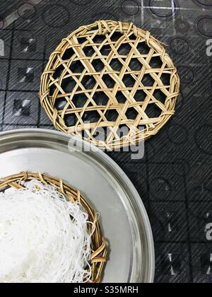 Trecce di riso o idiyappam aka Noolappam, pasta fatta in casa di farina di riso semi al vapore in Eco-friendly mano fatta mano foglia di palma piatto di ricetta Sud indiano-idiyappam con colore naturale, colazione indiana Foto Stock