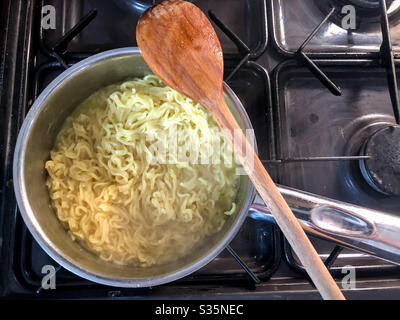 Una pentola di tagliatelle istantanee che cucinano su un fornello a gas. Foto Stock