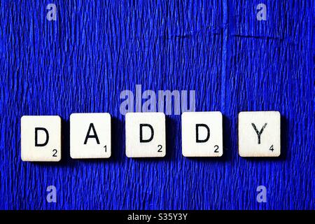 Piastrelle di legno che ortografano Daddy. Foto Stock