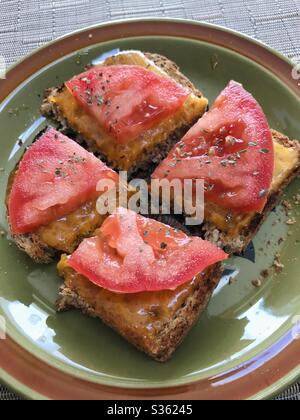 Tostare con formaggio fuso e pomodoro, tagliare a quattro pezzi su un piatto. Foto Stock