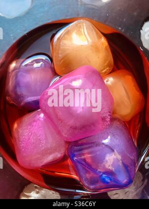 Cubetti di ghiaccio colorato in plastica in bevanda alcolica arancione Foto Stock