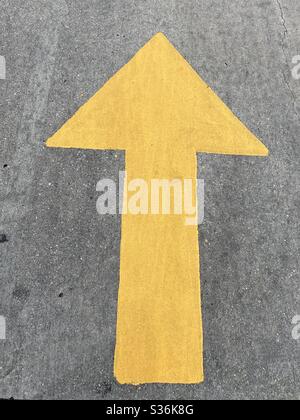 Grande freccia gialla dipinta su asfalto sulla strada Foto Stock