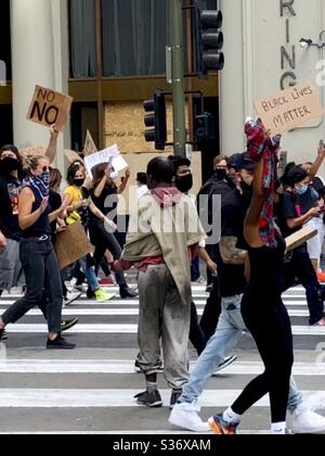 L'uomo senza tetto chiede denaro ai manifestanti che marciano nel centro di Los Angeles il 6.2.2020 Foto Stock