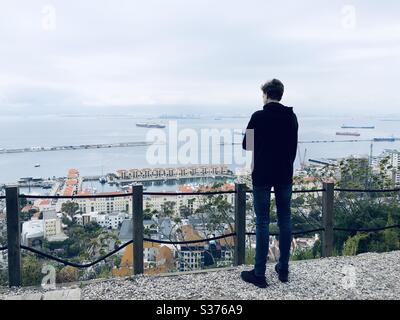 Ragazzo adolescente che guarda fuori sulla baia di Gibilterra dal punto di vista Foto Stock