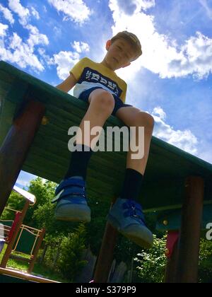 Bambino ragazzo seduto sulla cima del treno giocattolo in legno al parco giochi Foto Stock