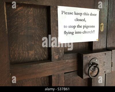 Firma su una porta della chiesa che spinge la gente a chiudere la porta per tenere i piccioni fuori Foto Stock