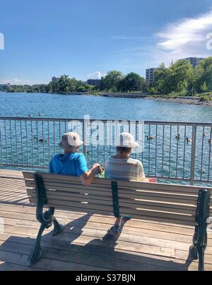 Una coppia anziana seduta su una panchina che gode della vista del mare. Foto Stock