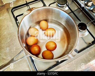 Vista closeup delle uova biologiche della fattoria a portata libera in una padella di acqua bollente. Preparare uova sode sul piano cottura. Bollire delicatamente su stufa a gas. Foto Stock