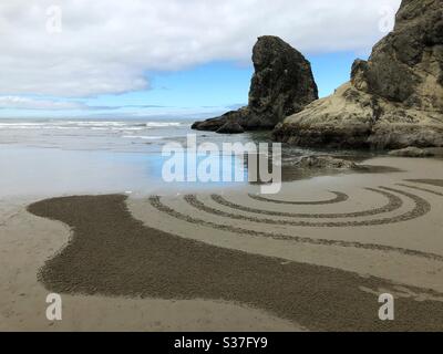 Marea crescente cancellando un labirinto di sabbia a Bandon, Oregon, Stati Uniti. Foto Stock