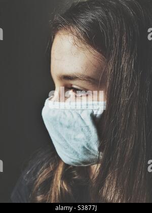 Vista laterale della ragazza adolescente che indossa una maschera di cotone bianco Foto Stock