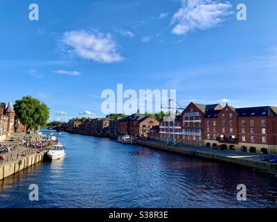 Il fiume Ouse che attraversa la città di York. Un sacco di persone sedette sulle panchine del pub locale, North Yorkshire, Inghilterra. Foto Stock