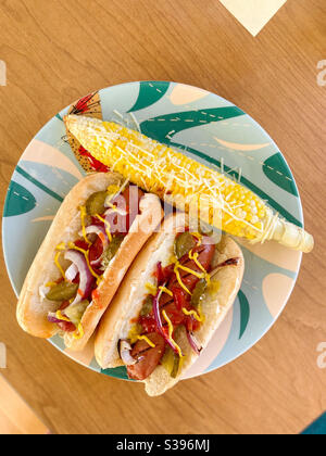 Un piatto con hot dog, condito con sottaceti, cipolle, ketchup e senape, e mais sulla pannocchia, condito con parmigiano, il Memorial Day Weekend, 25 maggio 2020. Foto Stock