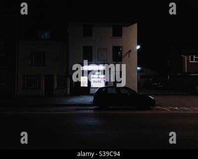 Strada scura illuminata dalle luci del negozio di takeaway cinese Foto Stock