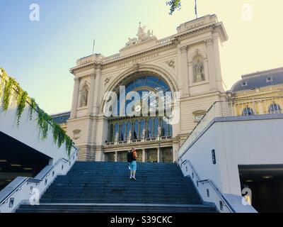 Facciata esterna di Keleti Palyaudvar (stazione ferroviaria di Keleti) con un passeggero che salta le scale, Budapest, Ungheria Foto Stock