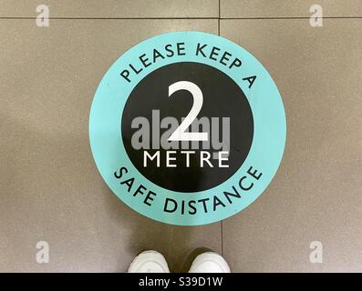 Adesivo sul pavimento di un negozio che ricorda ai clienti di necessità di un allontanamento sociale Foto Stock