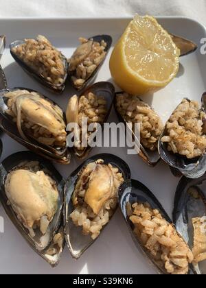 Cozze ripiene su un piatto di limone Foto Stock