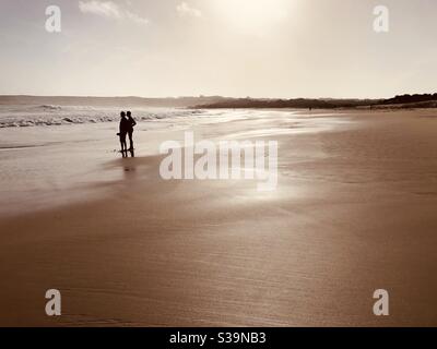 Silhouette di due persone su una spiaggia vuota in inverno Foto Stock