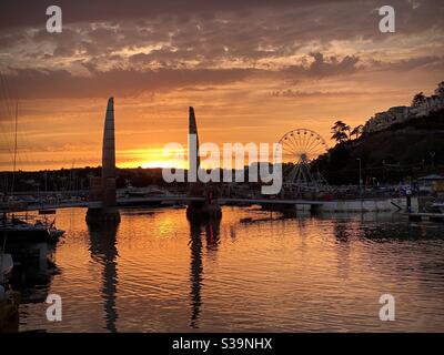 Un cielo colorato è gettato sopra il lato del porto durante il tramonto a Torquay in Devon, Regno Unito. Foto Stock