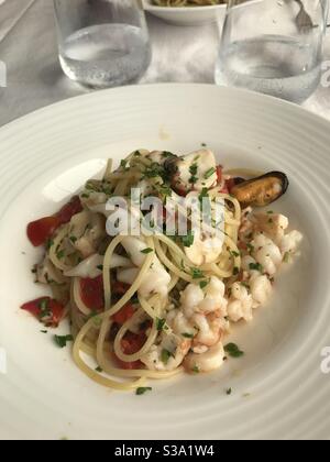 Un piatto tradizionale di pasta di pesce ‘spaghetti allo scoglio’ In un ristorante sulla costa italiana Foto Stock