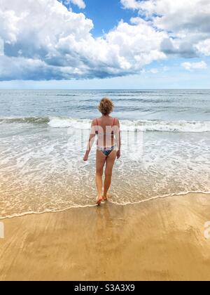 Donna in un bikini che cammina nell'oceano, Jacksonville Beach, Florida Foto Stock