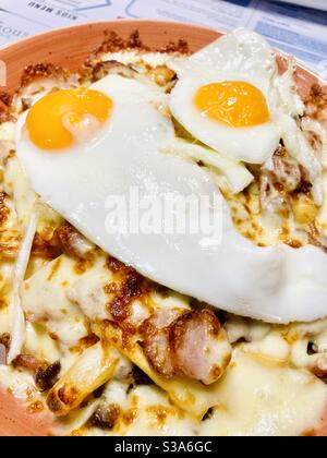 Patatine fritte e salsicce con uova fritte servite in un recipiente grande Foto Stock