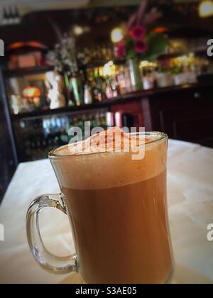 Cappuccino in una tazza di vetro trasparente servito in un elegante bistrot francese a Soho, New York City, USA Foto Stock